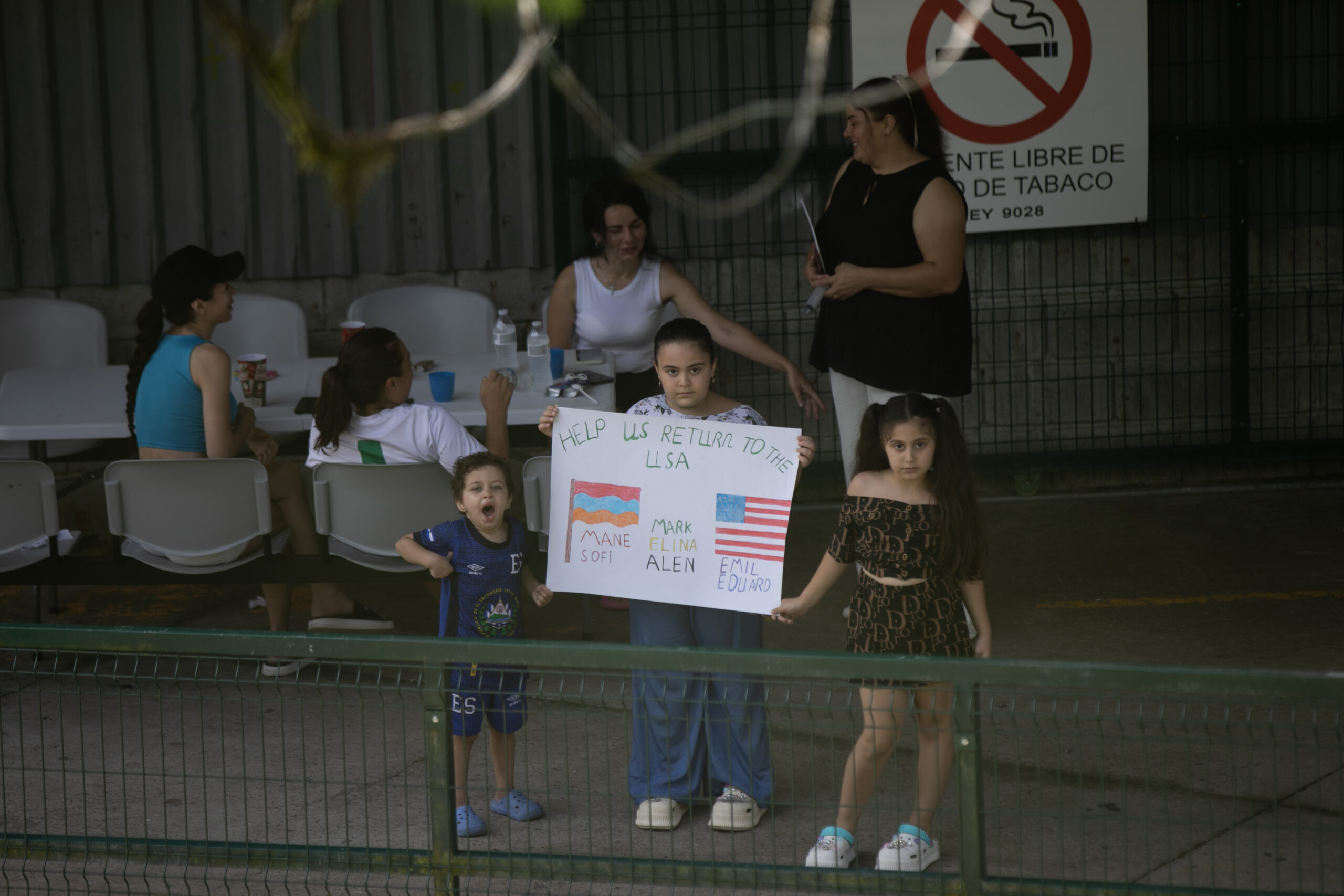 Un grupo de niños de Armenia sostienen un cartel con el mensaje: “Help us return to the USA” (Por favor, ayúdanos a regresar a Estados Unidos) | Foto: Galería News