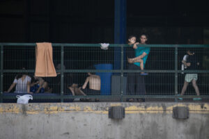 Una madre migrante carga a su hijo que saluda a los medios de comunicación que llegaron al CATEM, el lunes 31 de marzo| Foto: Galería News