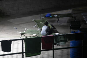 Una niña sentada en un catre en uno de los pasillos del CATEM, durante la noche| Foto: Galería News